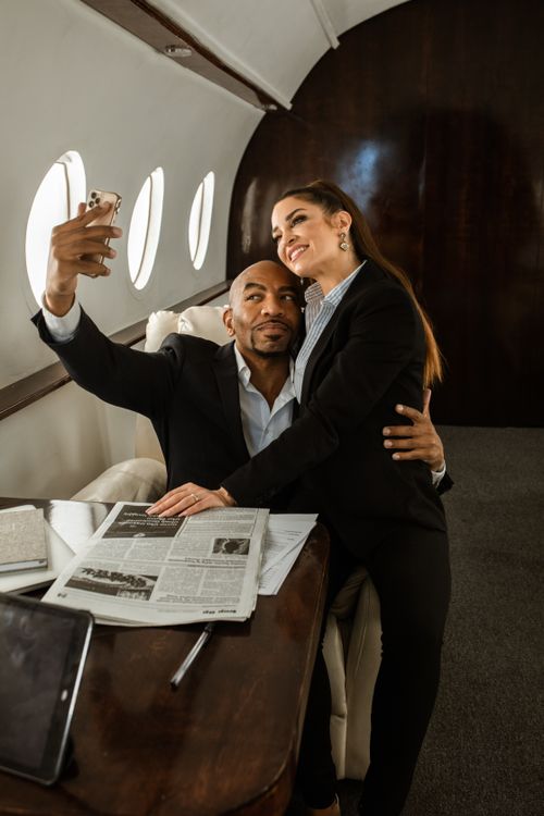 Free Happy couple taking a selfie in the cozy interior of a private jet, enjoying luxury travel. Stock Photo