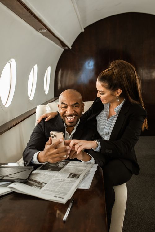 Free Business travelers engaging in a joyful conversation aboard a luxurious private jet, embracing a first-class lifestyle. Stock Photo