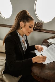一位穿着正式服装的自信女商人正在私人飞机上签署文件