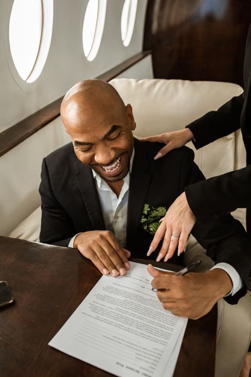 Free Businessman happily signing a document aboard a luxurious private jet. Elegant and professional setting. Stock Photo