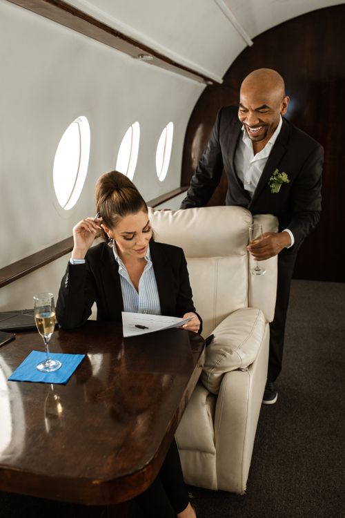 Free Elegant business travelers enjoying a luxury flight in a private jet, showcasing first-class comfort. Stock Photo
