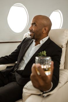 Man relaxing with drink in a private jet, exuding luxury and comfort.
