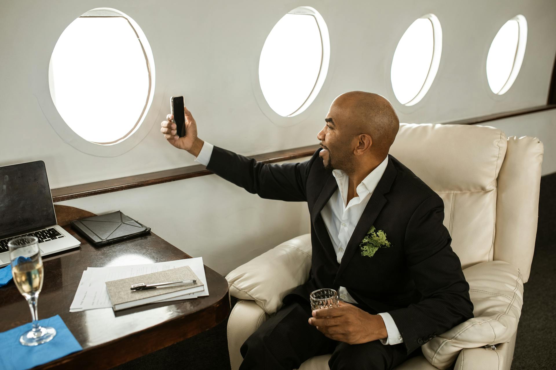 A businessman enjoying a drink and video call in a first-class private jet.