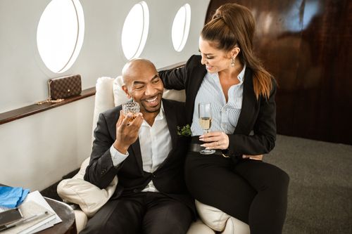Free Couple in suits enjoying drinks in a private jet, symbolizing luxury and elegance. Stock Photo
