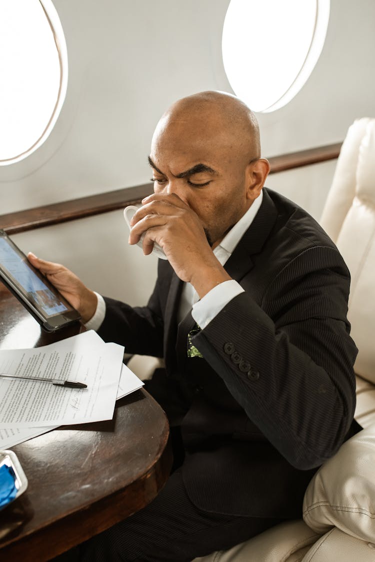 A Man Sipping His Drink In An Airplane