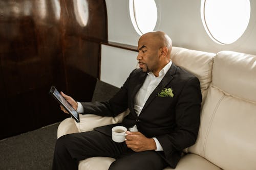 A Man in Black Suit Jacket looking at the Digital Tablet