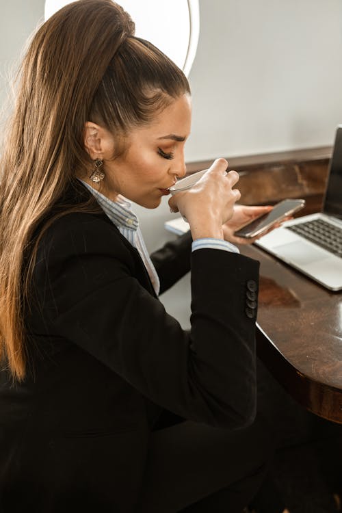 坐在餐桌旁使用macbook的黑色西裝外套的女人