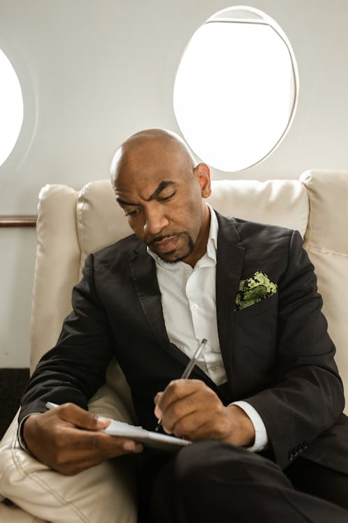 A Man in Black Suit Jacket Writing on White Paper
