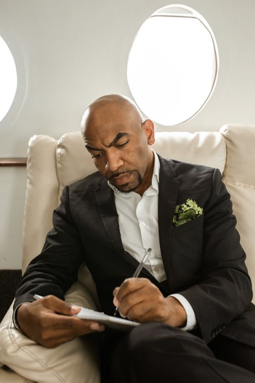 Free Focused businessman in a suit writing on a private jet. Professional travel setting. Stock Photo