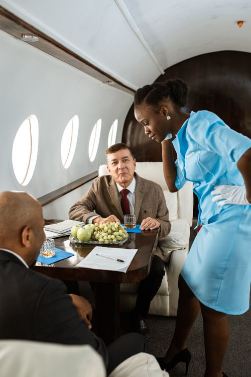Free Business professionals are attended by a stewardess during a meeting on a private jet. Stock Photo