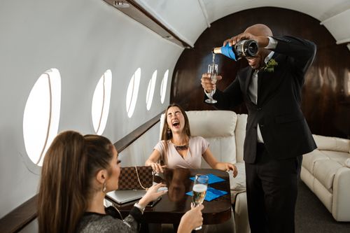 Free A joyful gathering of friends enjoying champagne on a private jet in a luxurious setting. Stock Photo