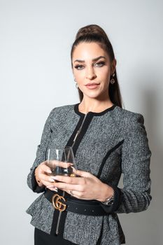 一位自信的女商人拿着玻璃杯站在一间时髦的室内