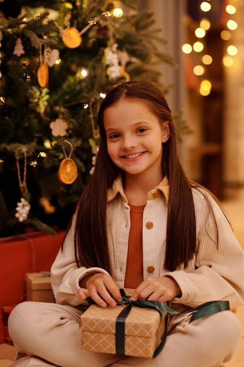 Девушка открывает рождественский подарок, улыбаясь