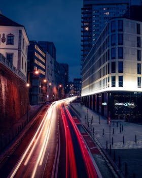Dynamic long exposure shot of a bustling Warsaw street at night, capturing light trails and urban architecture.