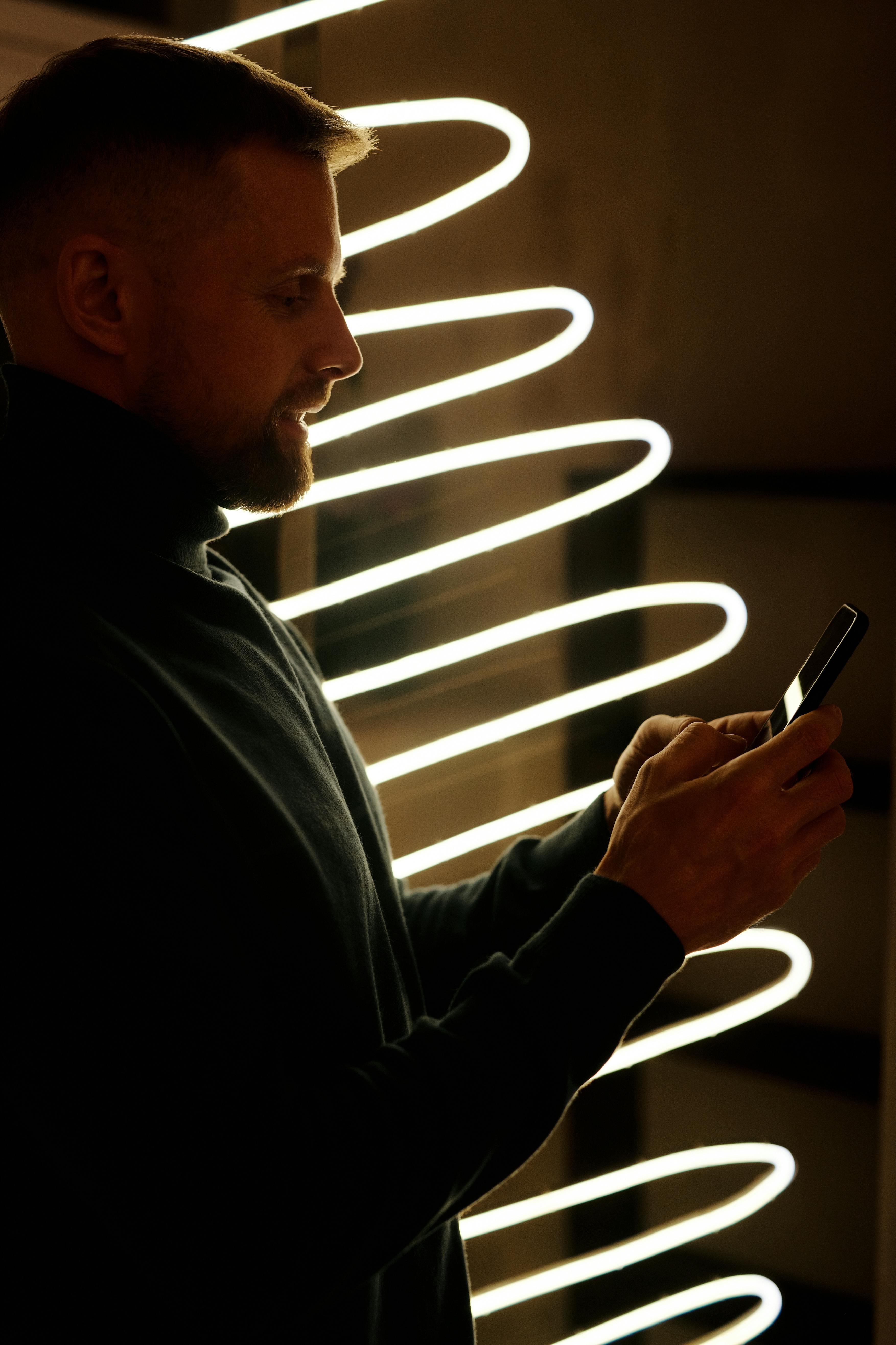 man in black long sleeve shirt holding smartphone