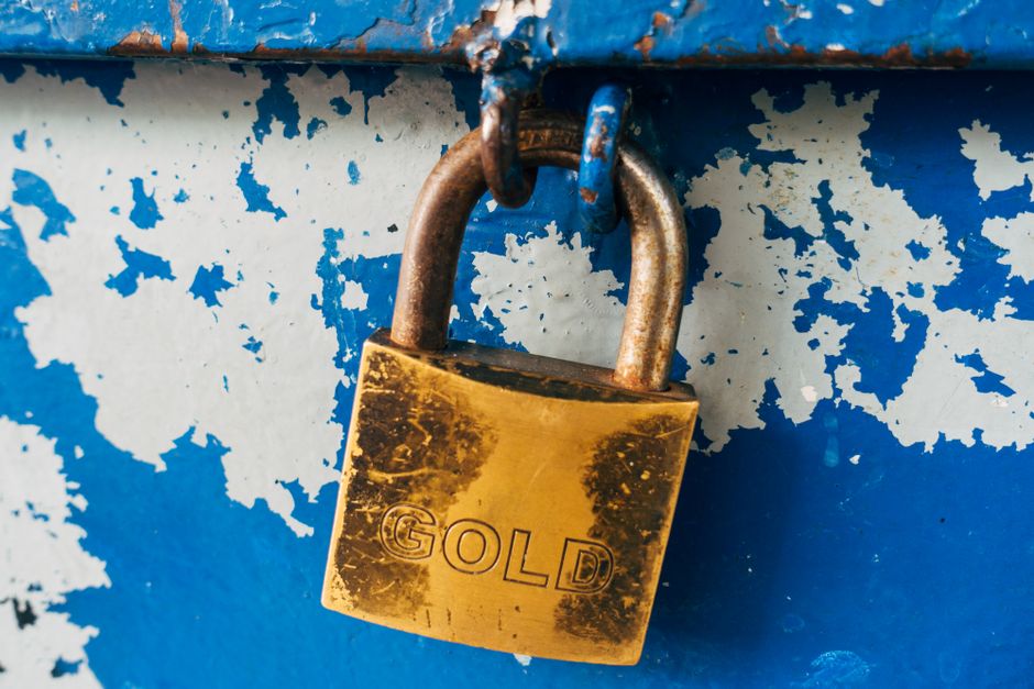 Detailed view of a rusty gold padlock labeled 'GOLD' on a weathered blue surface, Athens.