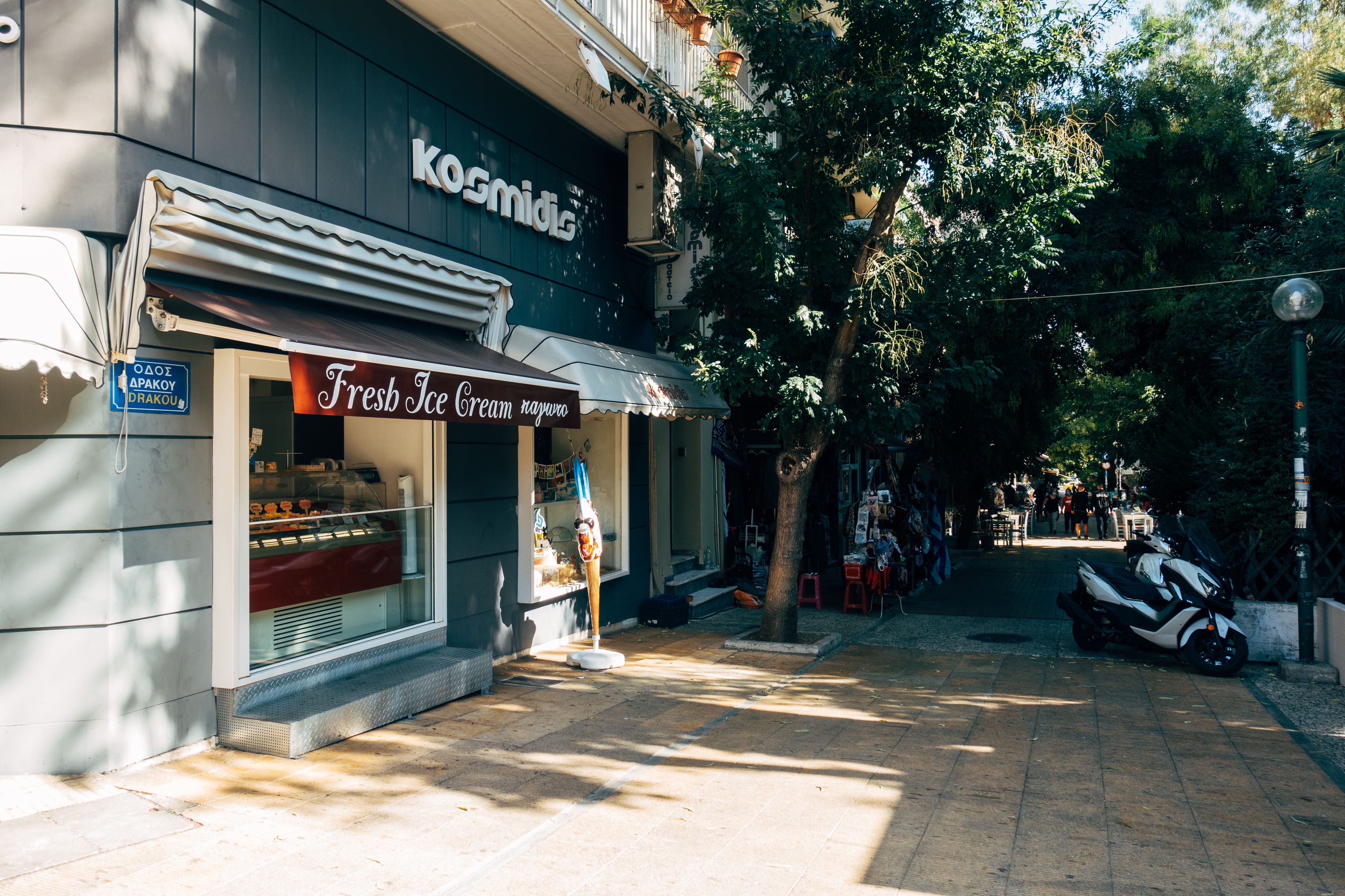 Cozy outdoor view of an ice cream shop on a sunny street in Athens.