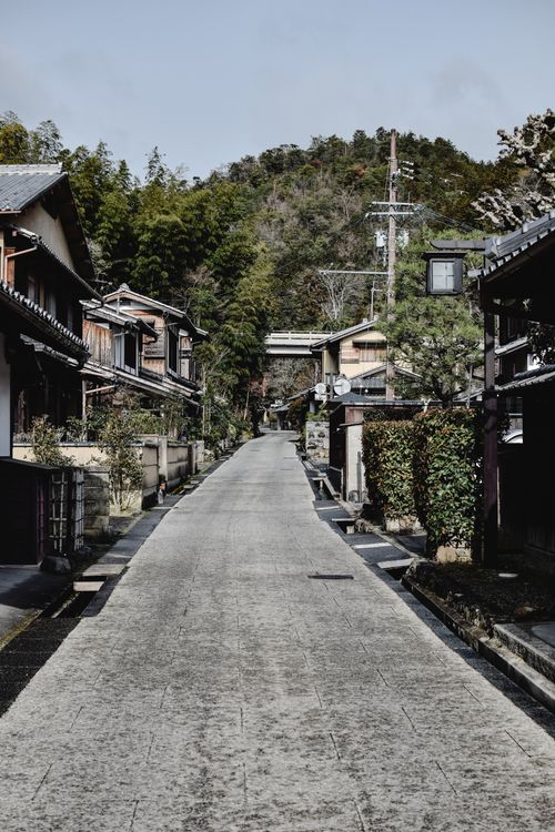 Free Explore a serene Japanese street lined with traditional wooden houses and lush greenery. Stock Photo