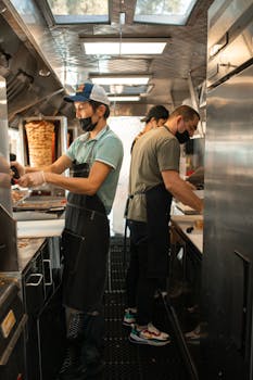 Chefs working in a food truck preparing delicious street food for customers.