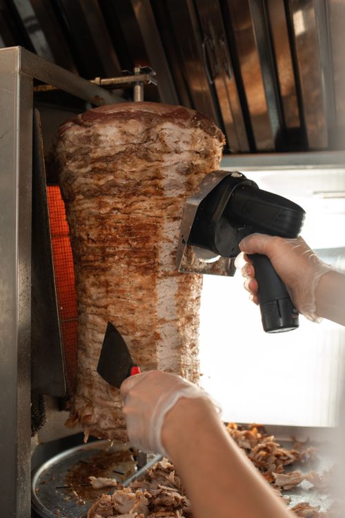 Free Close-up view of shawarma being sliced with professional equipment in a kitchen. Stock Photo