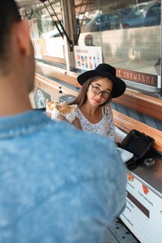 Woman enjoying street food at a food truck in a casual outdoor setting.