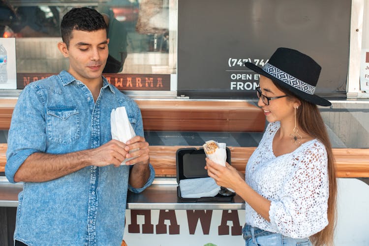 A Man And Woman Eating Shawarma