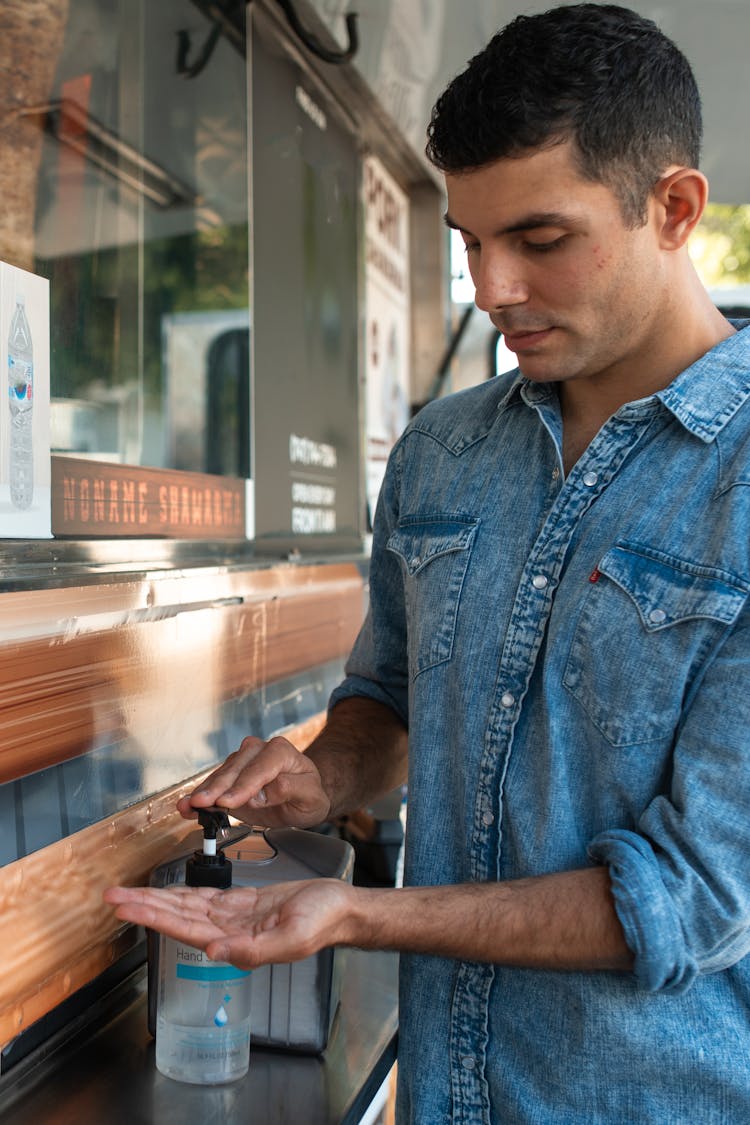 Man In Denim Dress Shirt Pumping The Bottle Of An Alcohol 