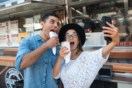 Two friends having fun eating shawarma and taking selfies at a food truck.