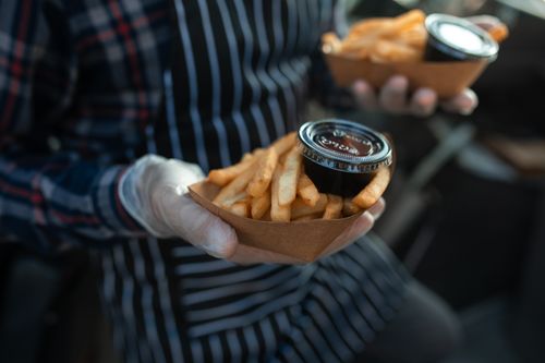 Free Crispy French fries served in a cardboard tray with dipping sauce, street food style. Stock Photo