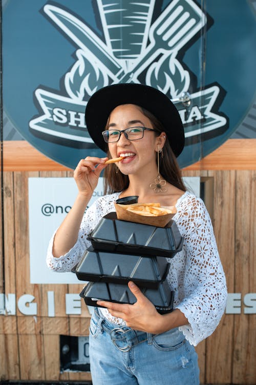 Free Beautiful Woman carrying Food Boxes while eating Fries  Stock Photo