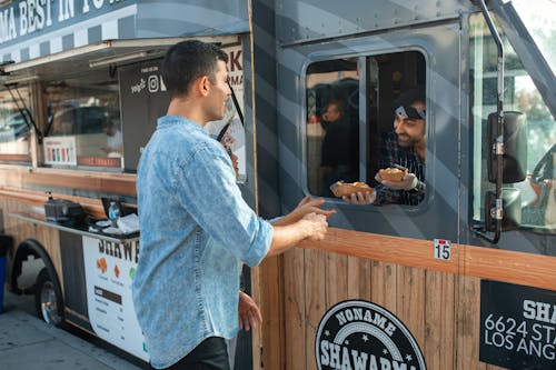 Free Man receiving orders from a Vendor on a Food Truck  Stock Photo