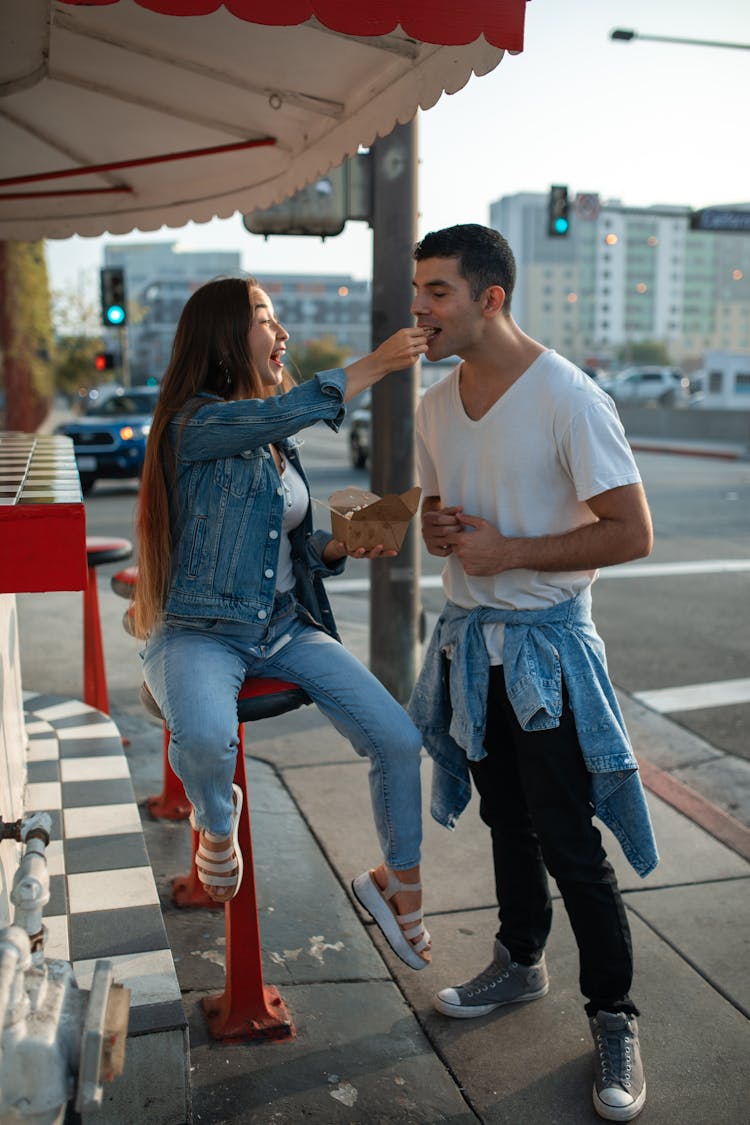 A Couple Eating Street Food On The Sidewalk