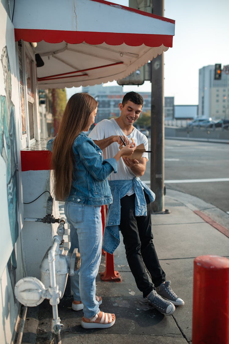 Friends Eating Food Beside A Food Stall 