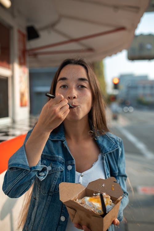 Woman in Blue Denim Jacket Eating