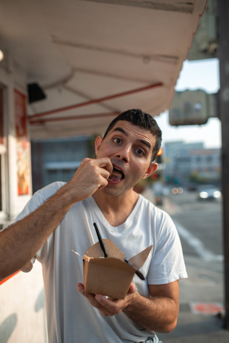 A Man In White Shirt Eating On The Street