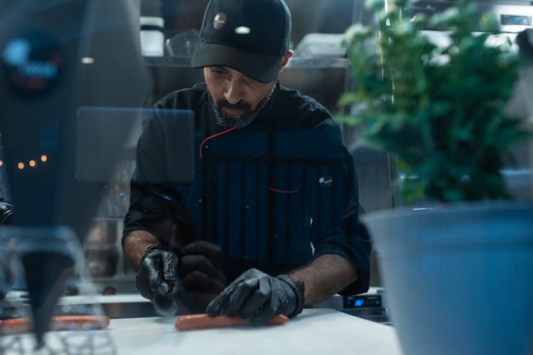 Close-up Photo Of Cook Slicing A Sausage