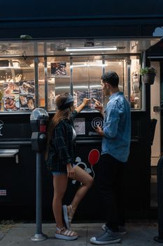 一对夫妇晚上在充满活力的街头食品卡车点餐，一起享受休闲时光