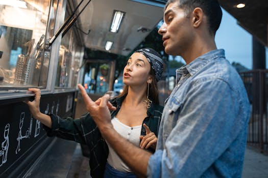 Young couple ordering food from a trendy street truck at dusk.