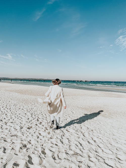 Anonymous woman walking on sandy beach