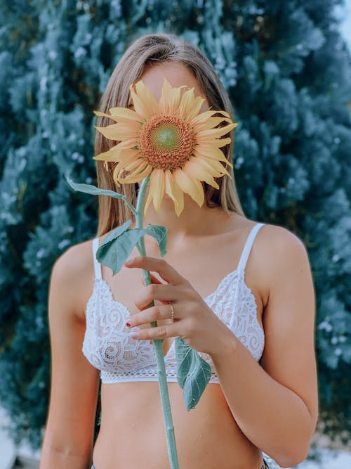 Unrecognizable woman covering face with flower