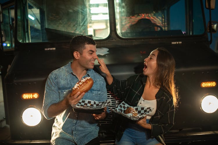 Man And Woman Eating In Front Of The Food Truck