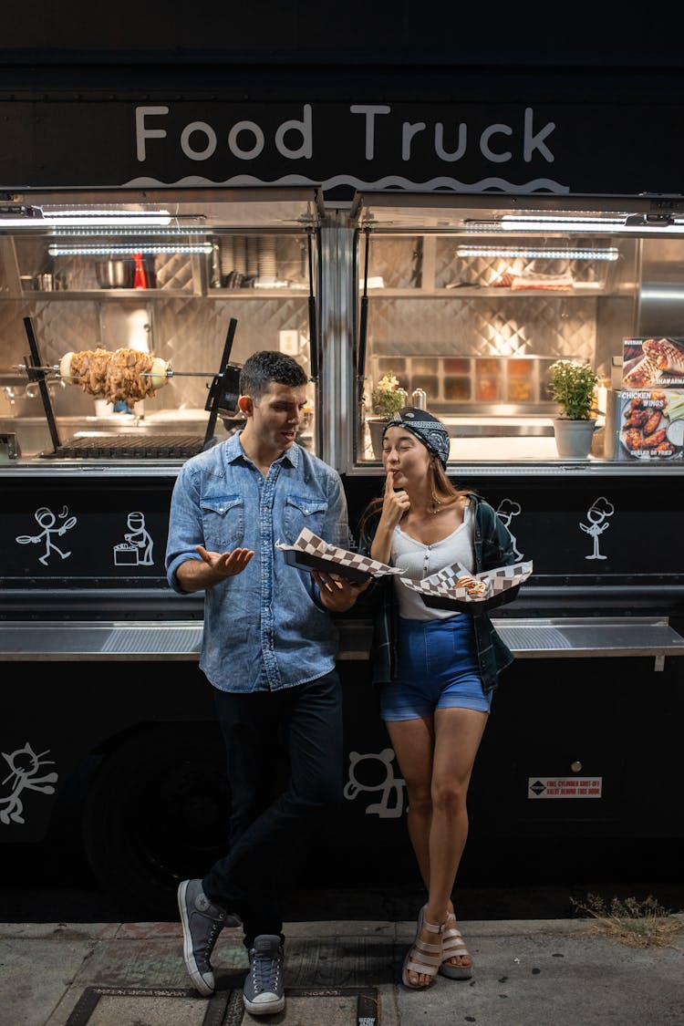 Man And Woman Eating In Front Of The Food Truck