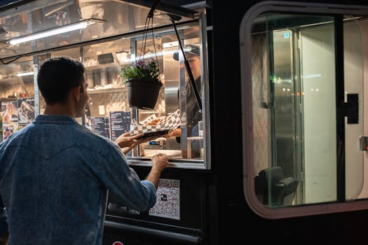 A man orders food from a food truck at night, showcasing urban street food culture.