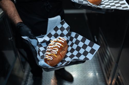 Free Delicious hot dog with toppings served in a commercial kitchen setting. Stock Photo