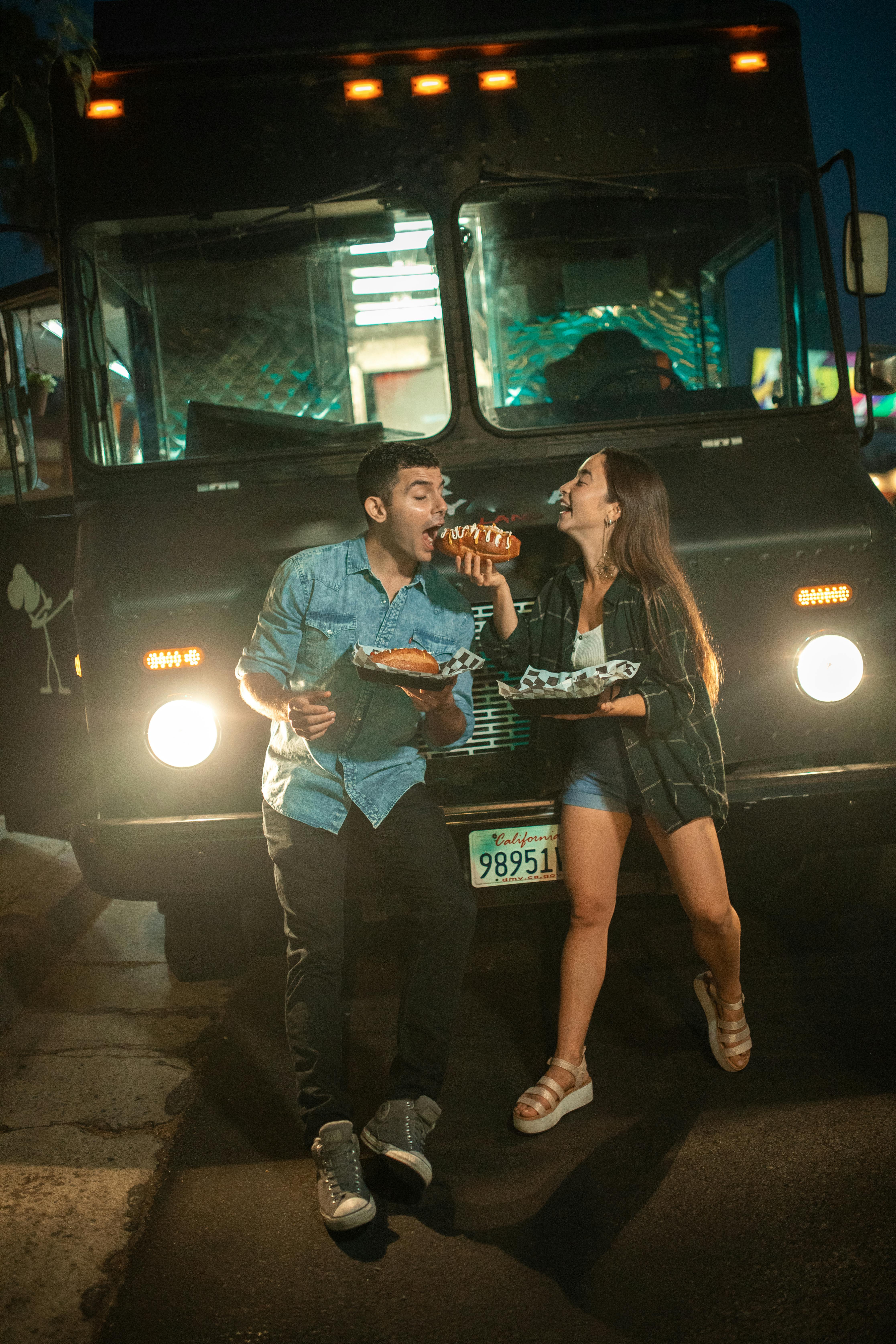 a couple in front of a food truck eating together