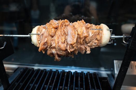 Close-up of raw chicken shawarma being grilled on a skewer, ready for cooking.