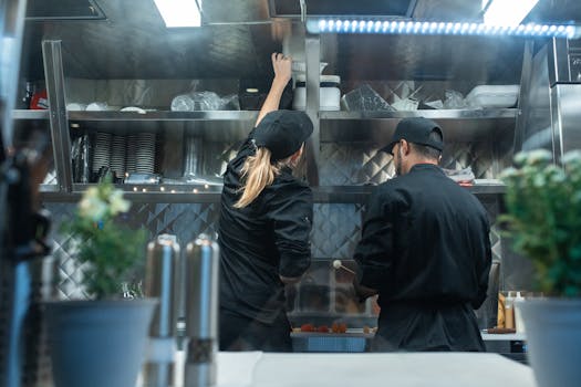 Two chefs working together in a commercial kitchen, preparing food.