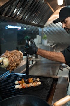 A street food vendor seasons kebabs on a grill while preparing shawarma in an outdoor kitchen.