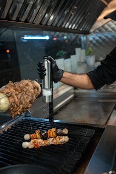 A chef preparing tasty kebabs on a grill at a modern restaurant kitchen.