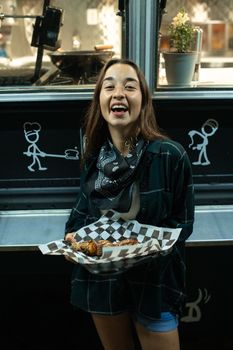 一位微笑的女子在餐车前拿着街头美食，展示着城市街头的风味